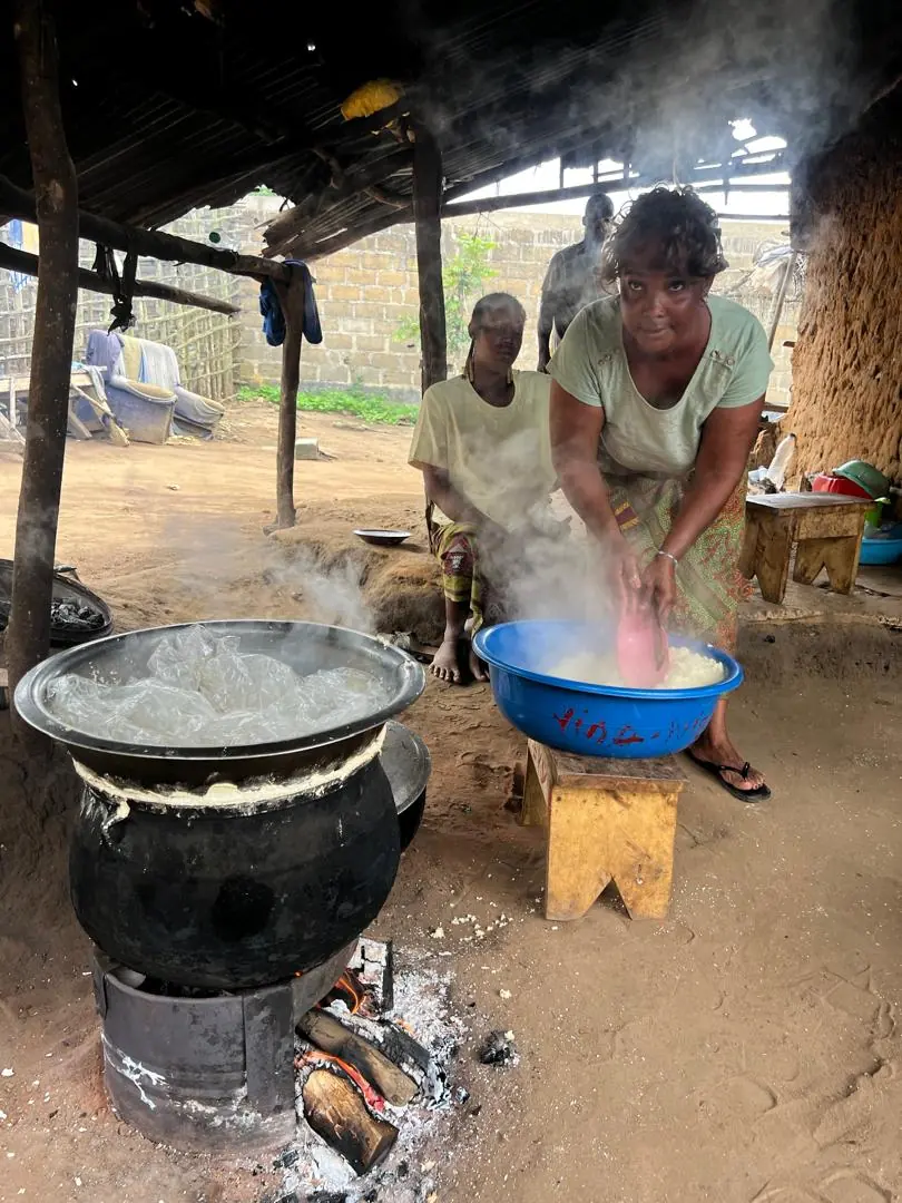 Une productrice remue la semoule de manioc fumante au-dessus du feu, à Orbaff