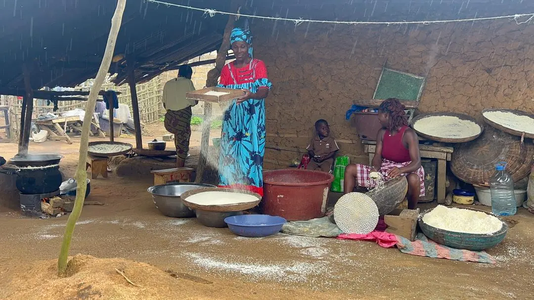 Une productrice tamise la semoule d'attiéké malgré la pluie, à Orbaff