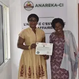 ANAREKA-CI's Secretary General with her GR-IGP Attiéké des Lagunes Ambassador appointment certificate at headquarters